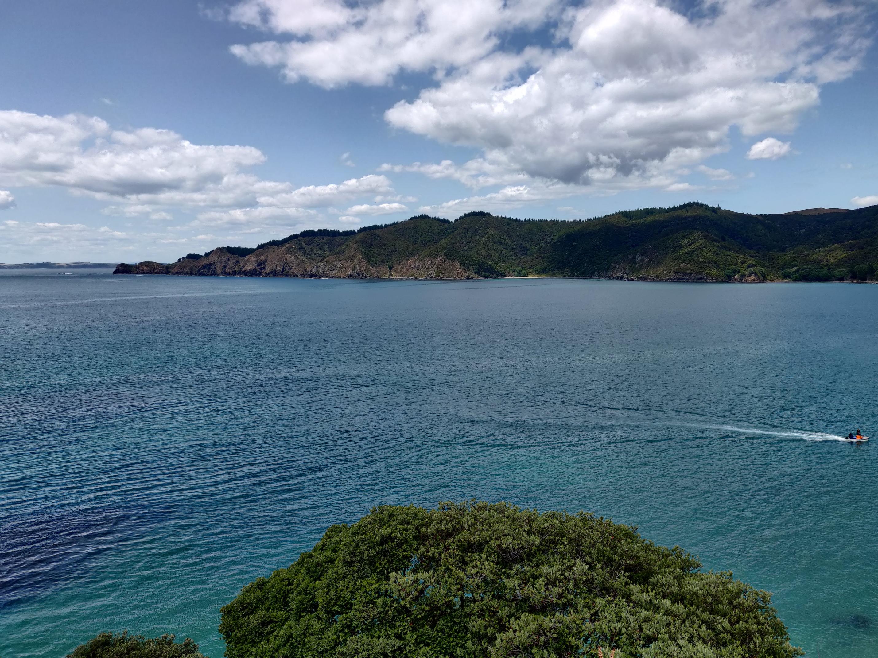 image of the ocean with distant green hills, with a boat riding past in the middleground