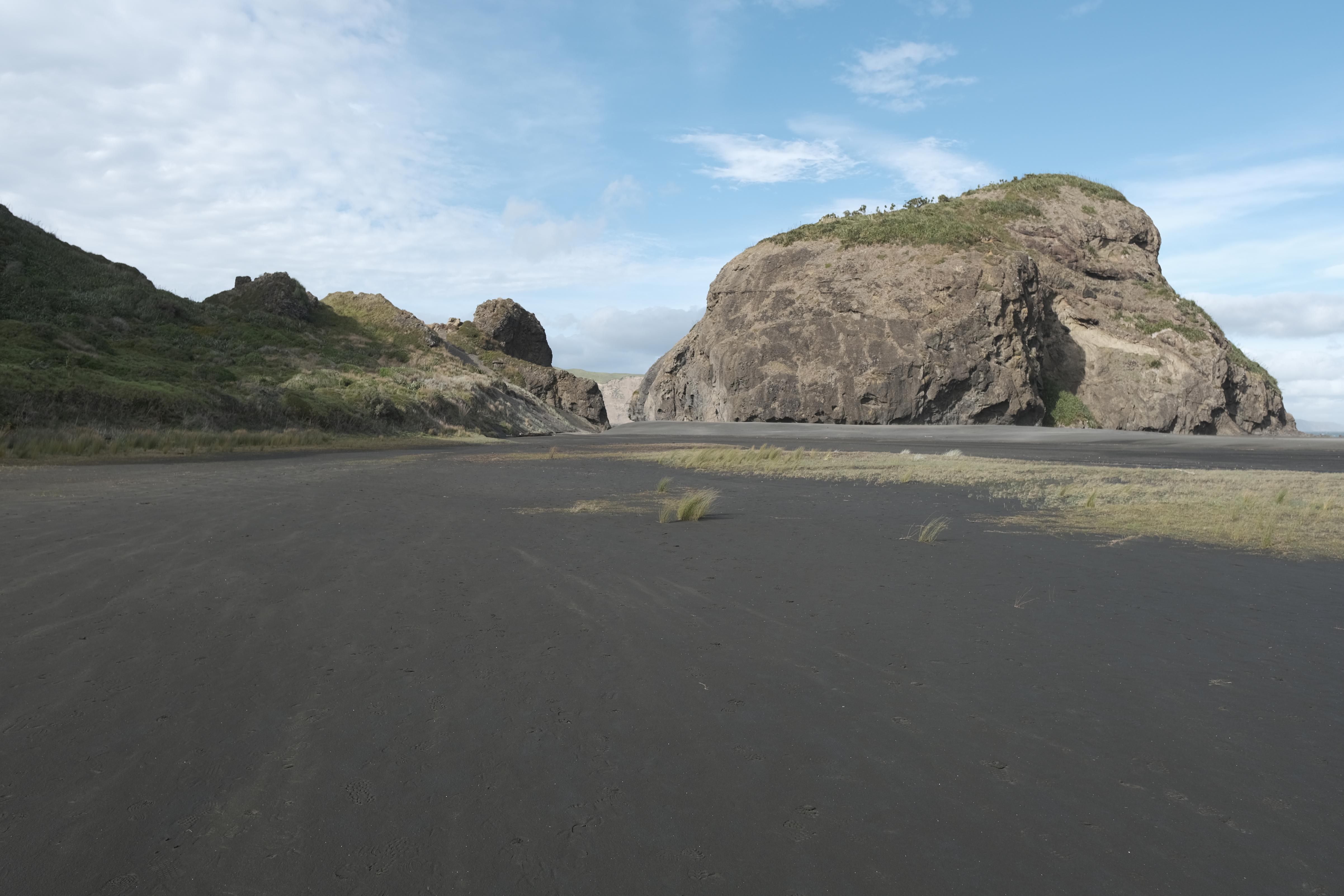 image of black sandy beach with steep cliffs in background
